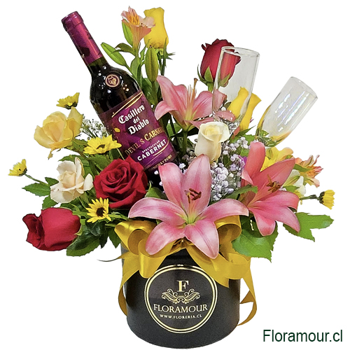 Caja cil&iacute;ndrica con flores variadas coloridas, botella de vino tinto cabernet y par de copas de vidrio.